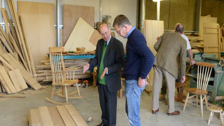 men looking at timber in workshop with a rocking chair