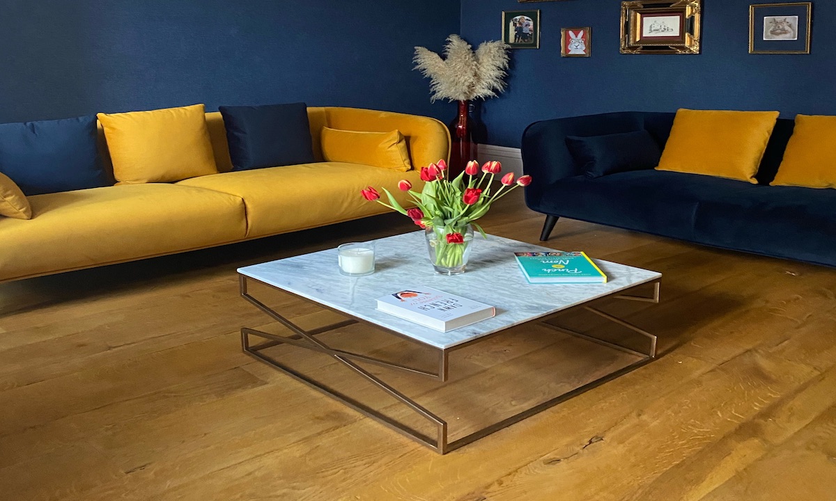 oak flooring dark blue painted sitting room mustard and yellow sofas and yellow cushions.