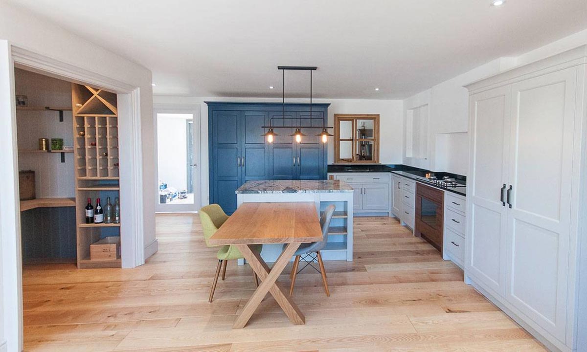 kitchen table to seat two people with light grey kitchen cupboards and larder area