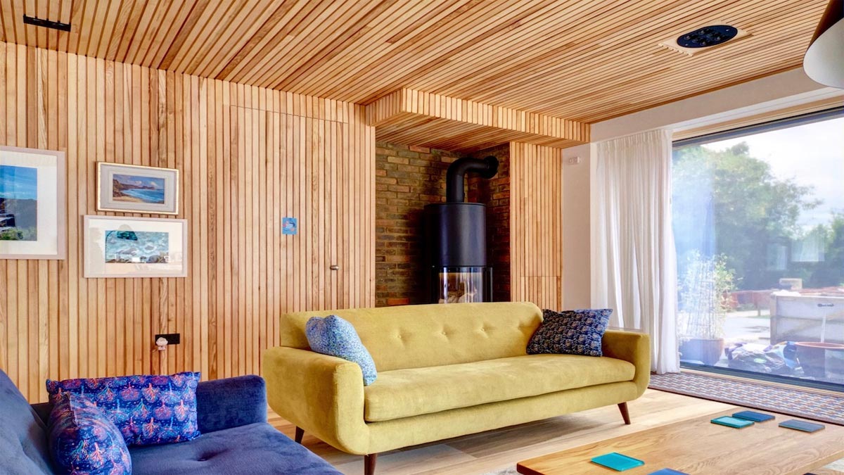 strips of ash cladding in modern room with large woodburner and two sofas overlooking the garden