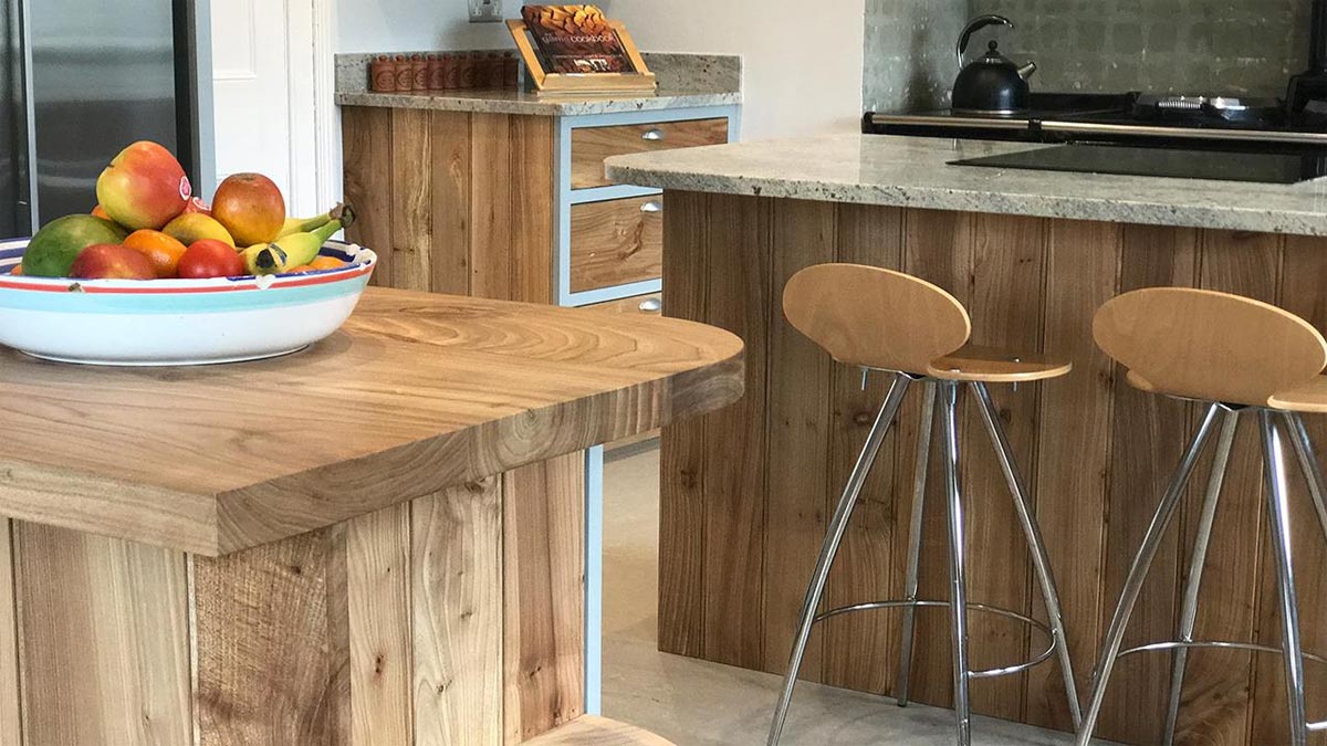 two bar stools around kitchen island with wood work surface and fruit bowl