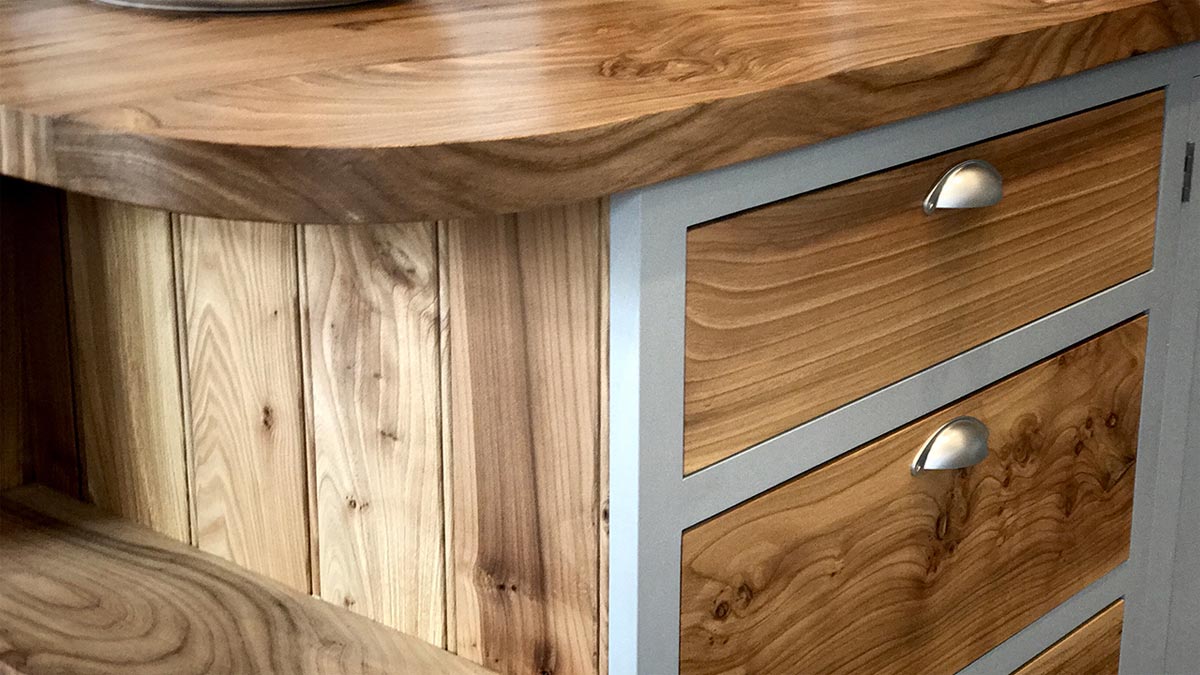 curved corner of elm work top in kitchen with stainless steel cup handles