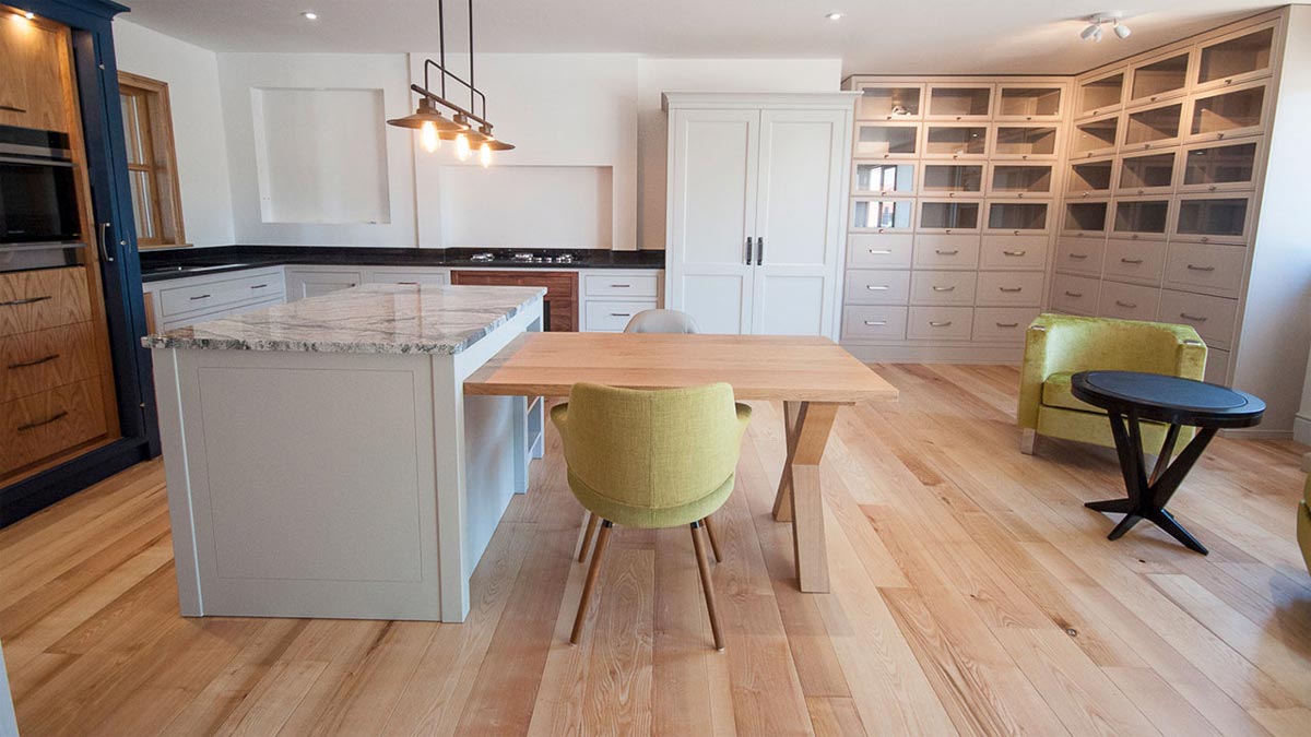 kitchen with grey cupboards and dark grey marble island and wood floor