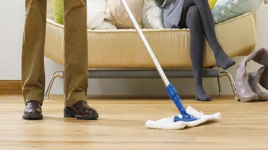 person sitting on sofa with person mopping floor with fabric brush