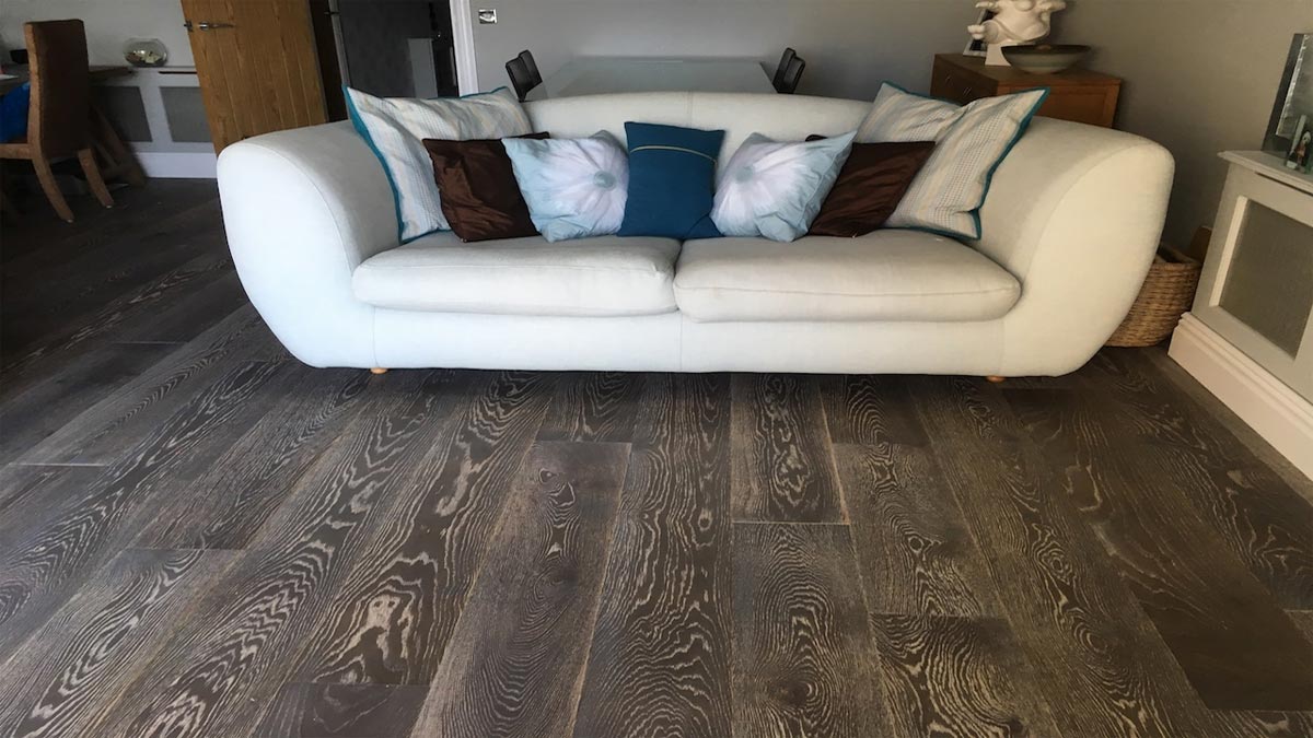 large white sofa with cushions in a sitting room with grey engineered oak flooring