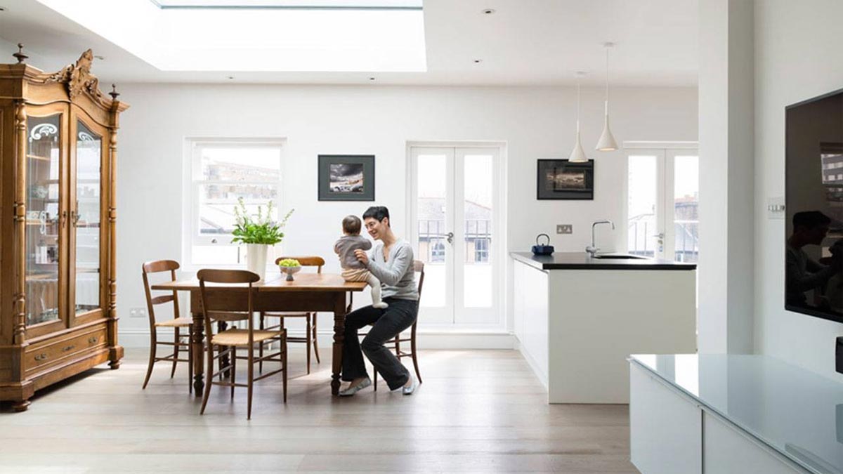 woman sitting at table holding child in light filled kitchen