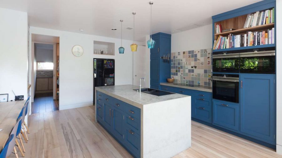 blue kitchen island with ash flooring bookshelves and ovens