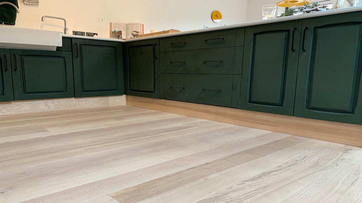 wood floor in kitchen with dark green cabinetry