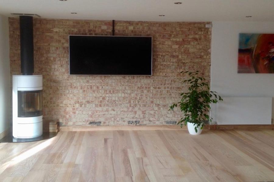 engineered ash sitting room floor with woodburner and brick feature wall