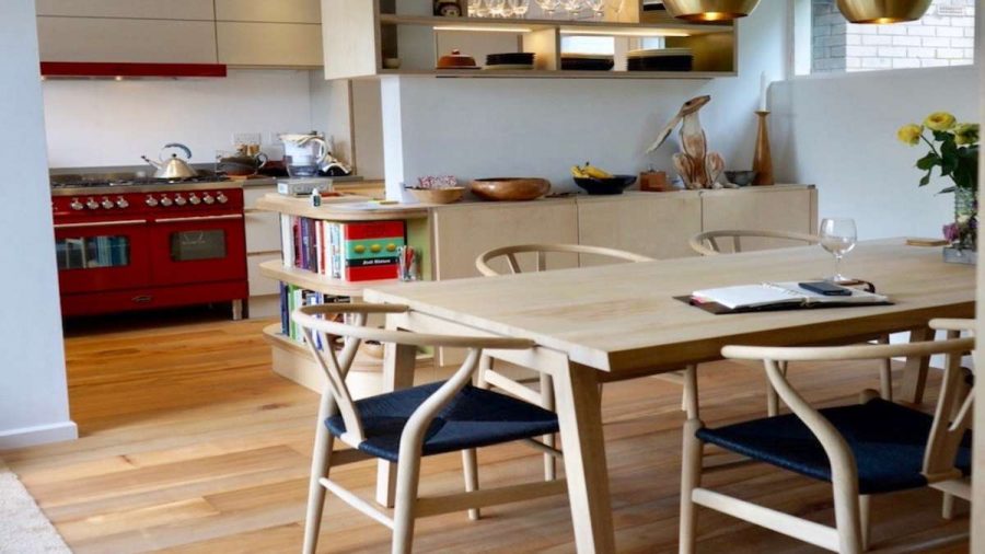 pale wood kitchen table and chairs with red range cooker and fruit bowls