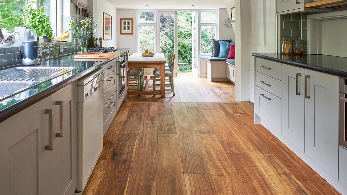 Grey galley style kitchen cabinets with elm wood floor and view to garden