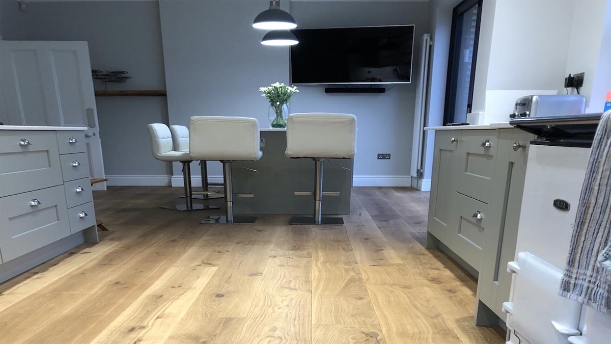 white kitchen stools around island with large tv mounted on wall