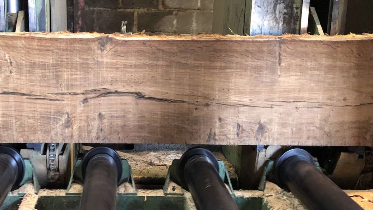 brown oak board on machine being milled into boards