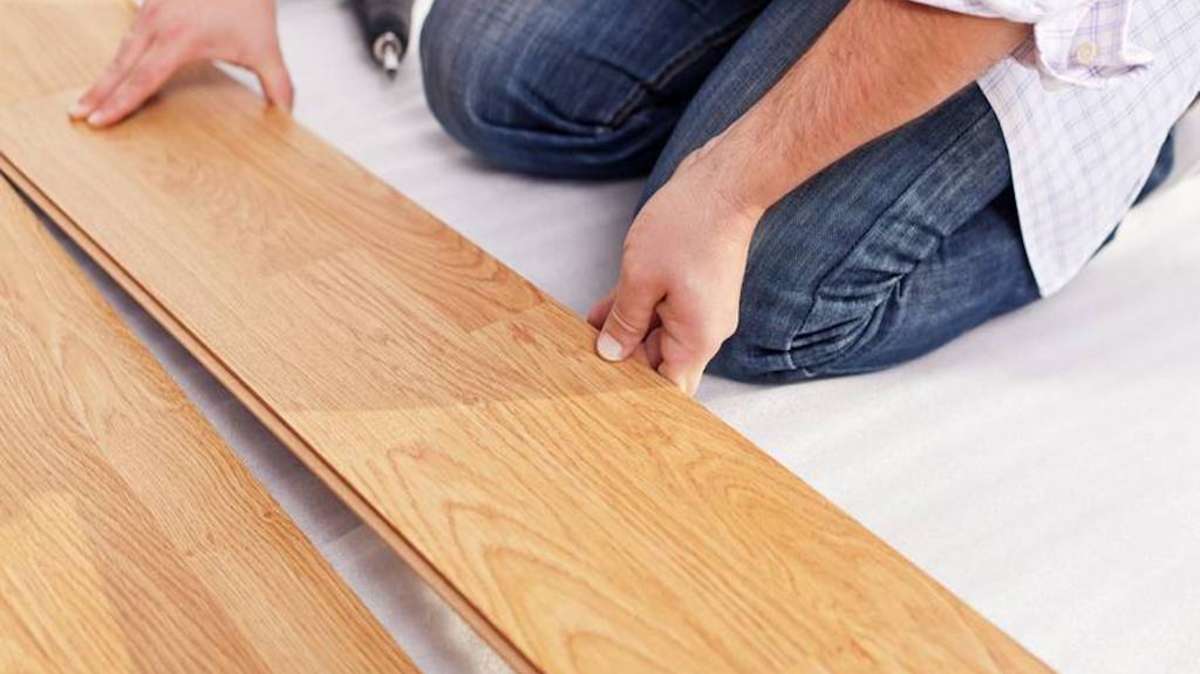 person on knees laying wood flooring
