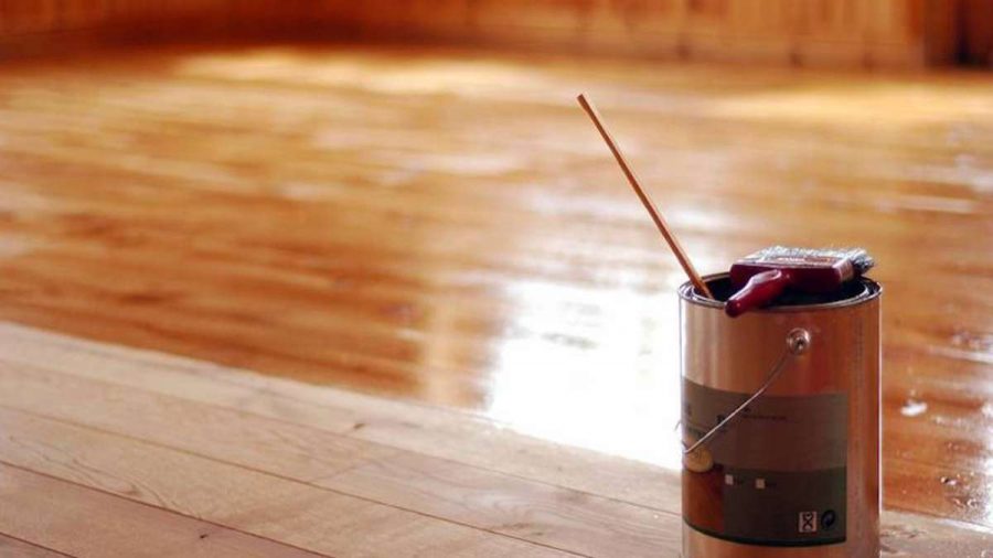 paint tin with brush on top and stirring stick showing floor part varnished