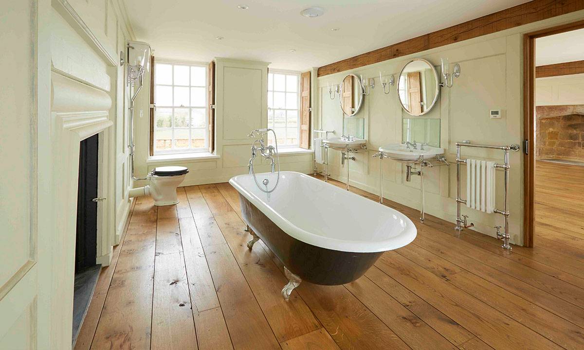 roll top batch in the middle of bathroom with twin basins and mirrors and solid oak flooring