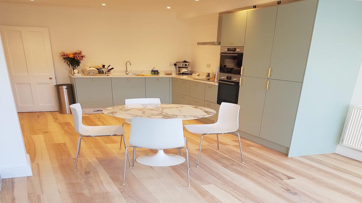 pale green kitchen cupboards with round table and white chairs