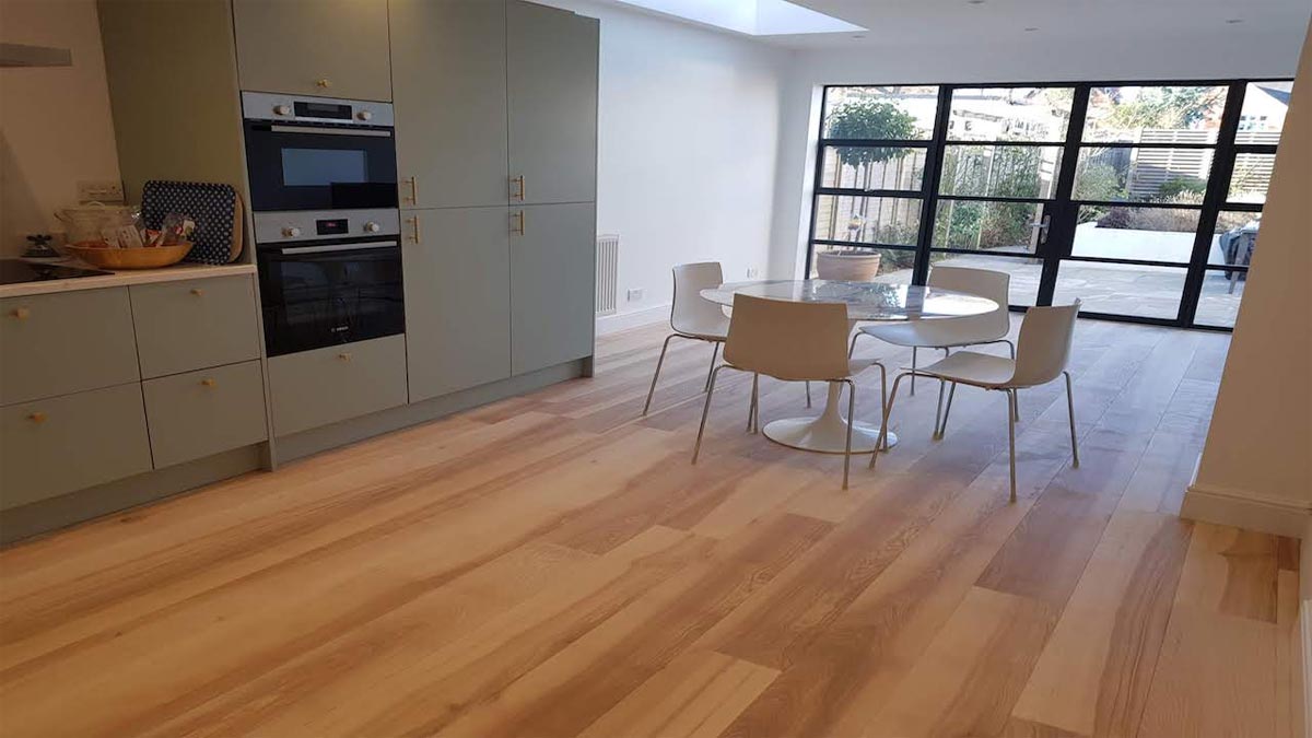 kitchen with central glass dining table leading to terrace with crittal style windows