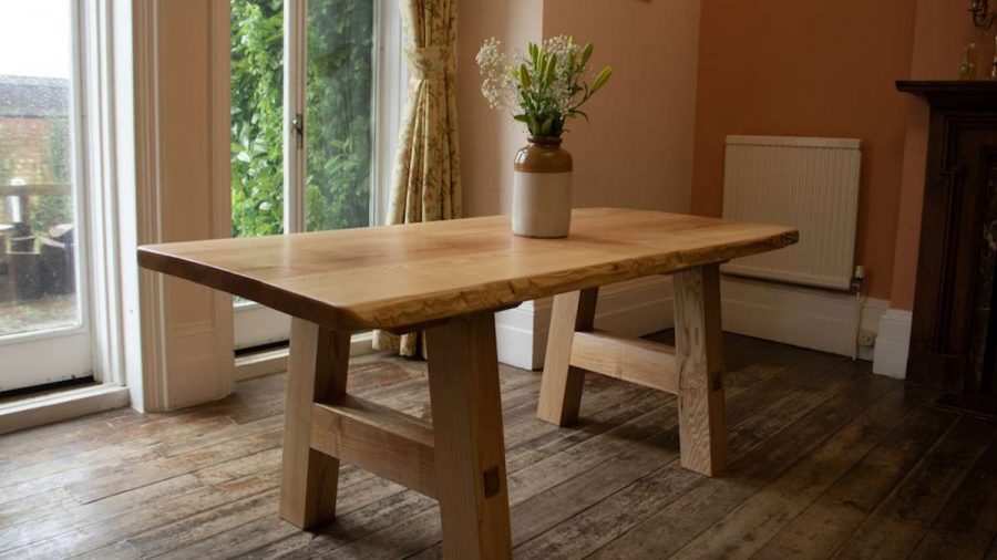 oak table in room with a vase of flowers on top in room with windows to terrace