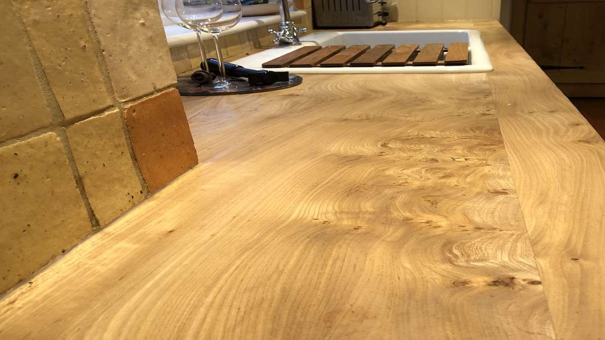 elm work surface in kitchen with drainer in view and wine glasses