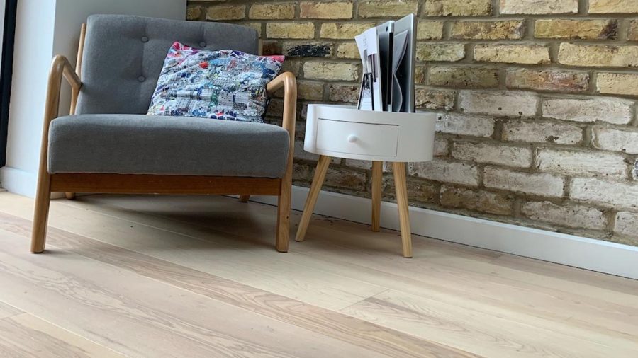 light ash flooring with comfy chair and table with magazine rack besides and brick walls