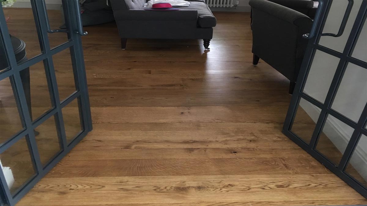 oak flooring with glass steel framed doors leading the sitting room