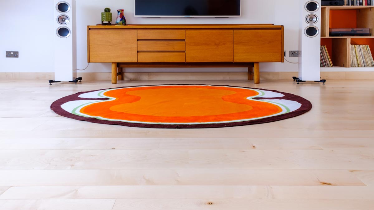 round orange rug in room with tv on wall over sideboard