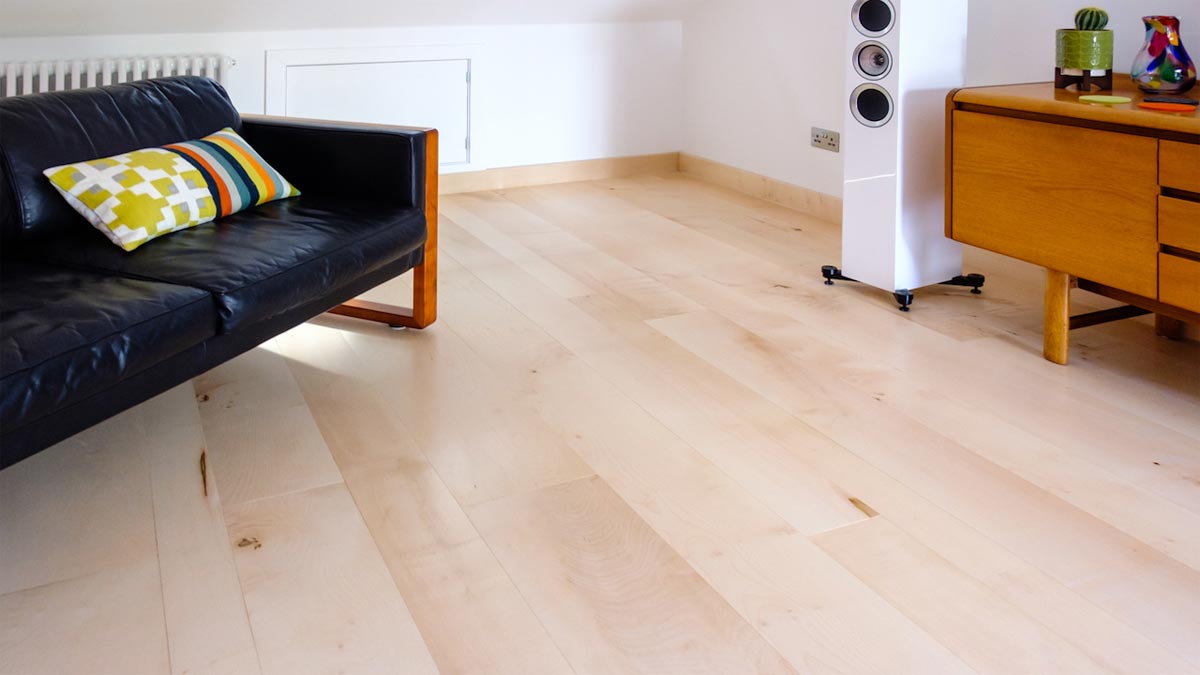 sitting room with pale wood floor and black sofa