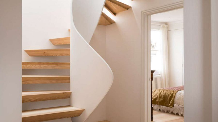 sprial open staircase with white balustrade and view through open door to bedroom with velvet throw on bed
