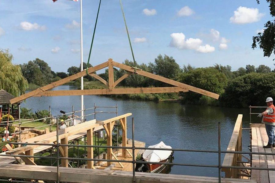 structural oak a frame being lifted over river