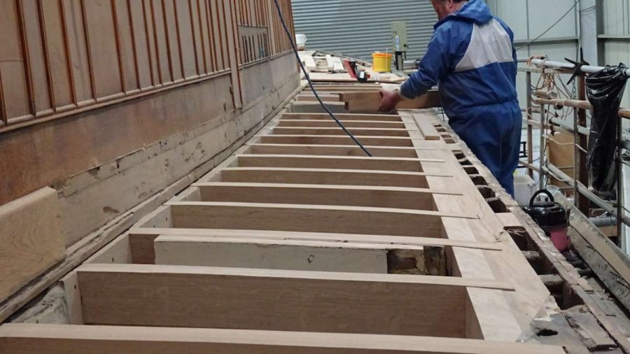 man working on a repairing a timber framed boat