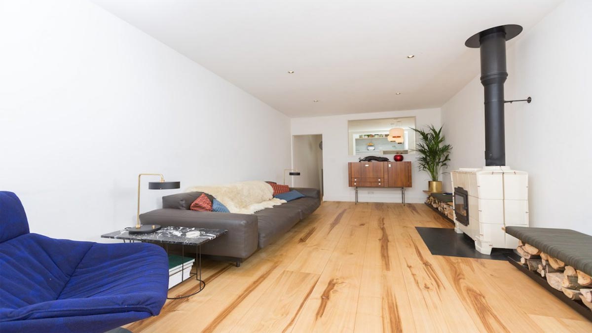 sitting room with large black leather sofa white woodburner and opening to kitchen